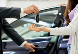 two hands exchange car keys against a car background