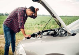 a man stands in front of a car with the hood open