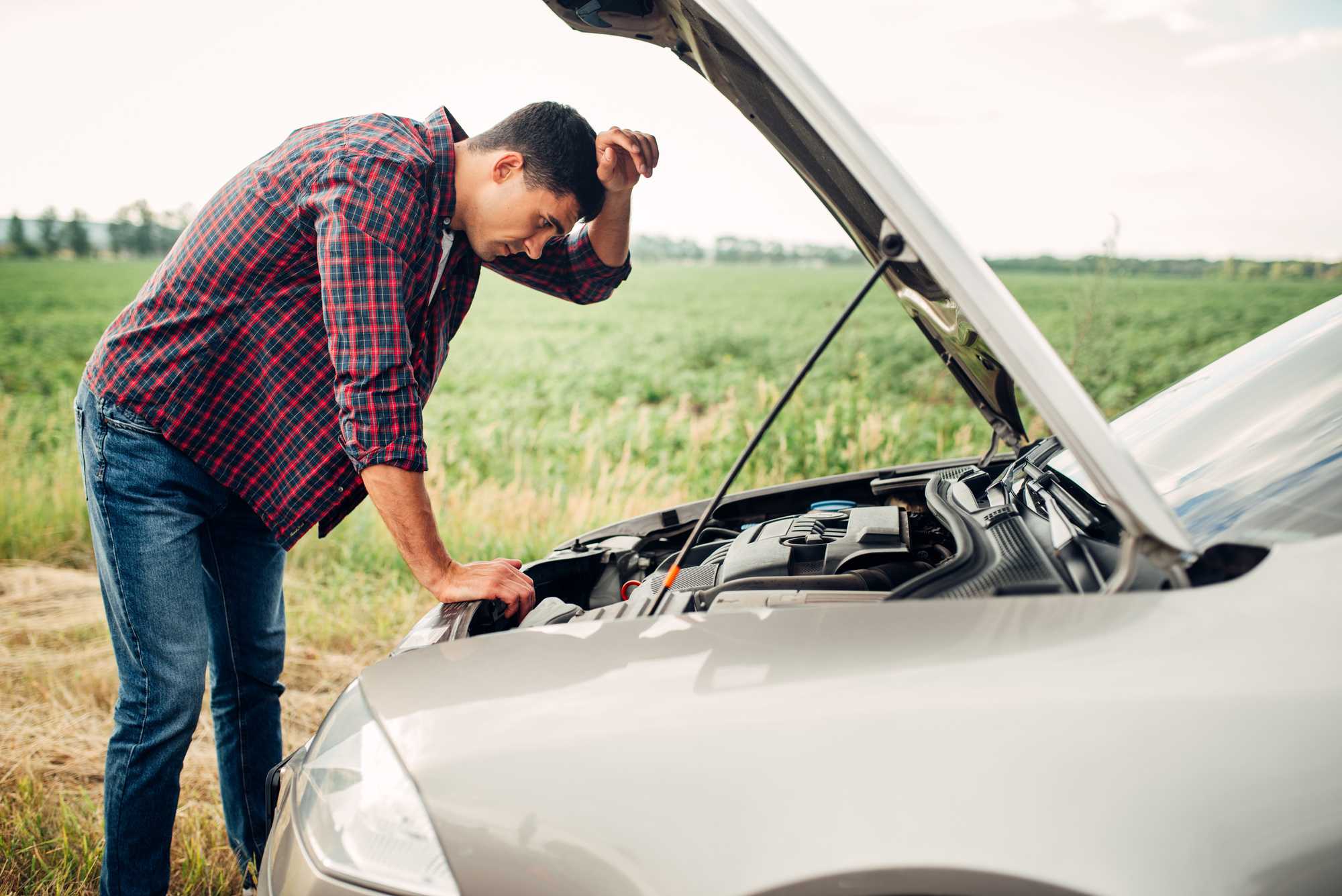 a man stands in front of a car with the hood open