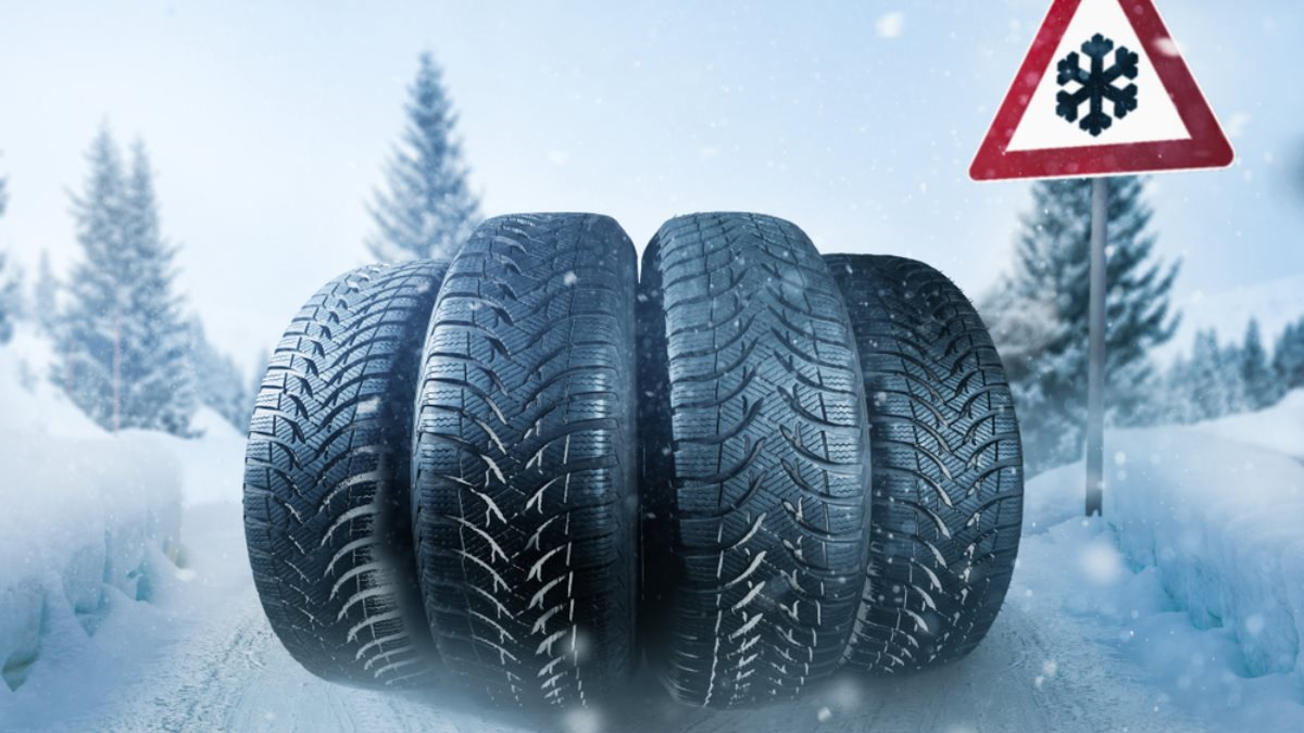 four winter tires next to a snow road sign