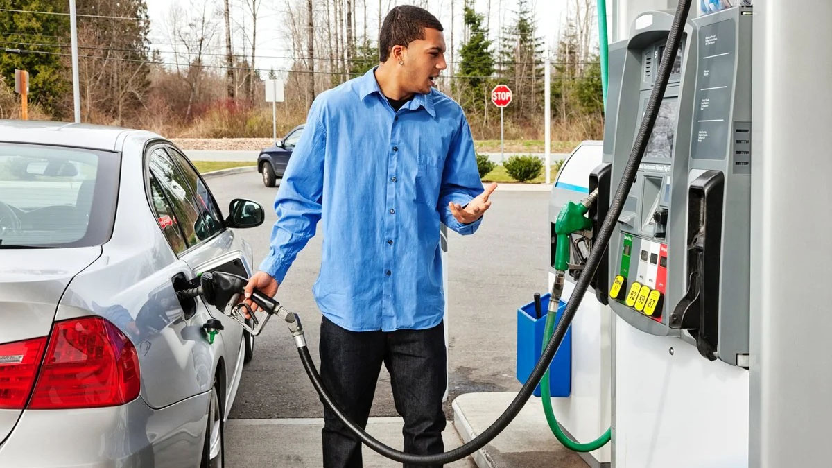 A man fills up with petrol at a gas station on the highway