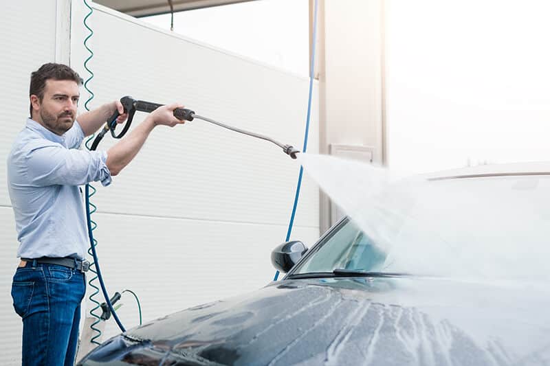 a man washes his car at a self-service car wash
