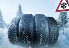 four winter tires next to a snow road sign